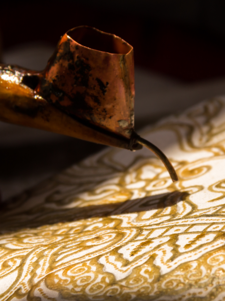 Batik tulis being made by hand with hot wax and a traditional canting.