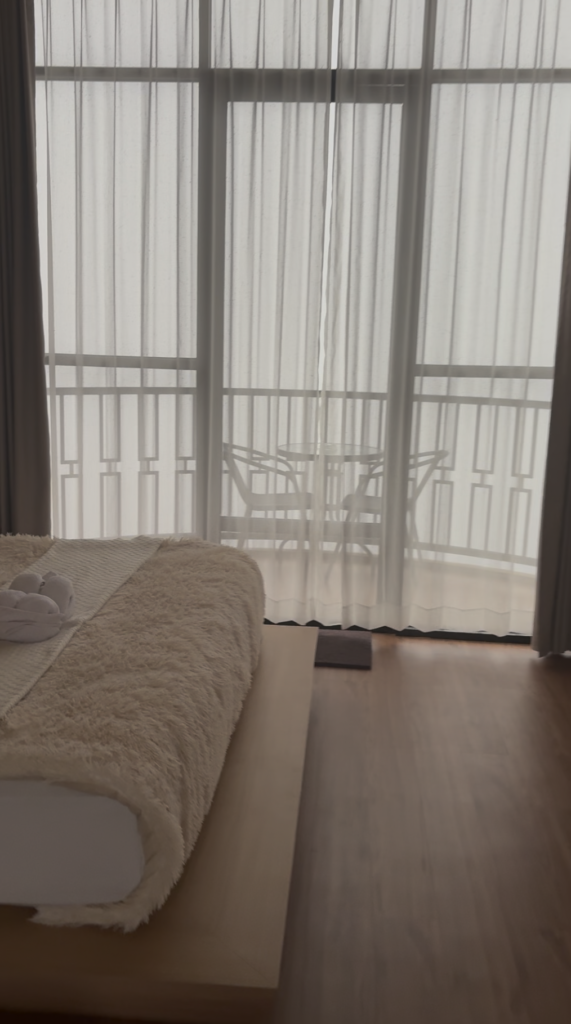 Hotel room with floor-to-ceiling windows overlooking a foggy landscape near Dieng, Central Java.