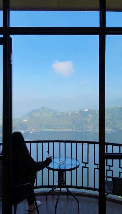 Clear morning view of a lake and green hills from a hotel room balcony near Dieng, Central Java