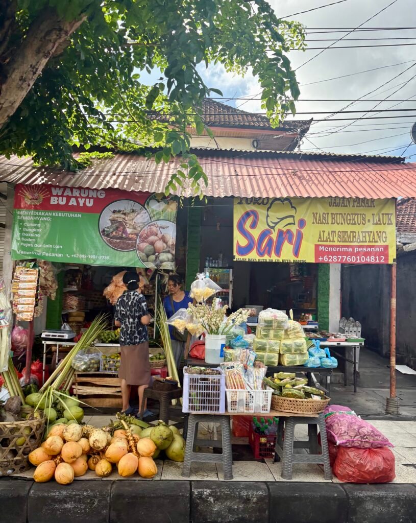 Small roadside warung selling coconuts, food and prayer offerings on Jalan Raya Kuta in Bali