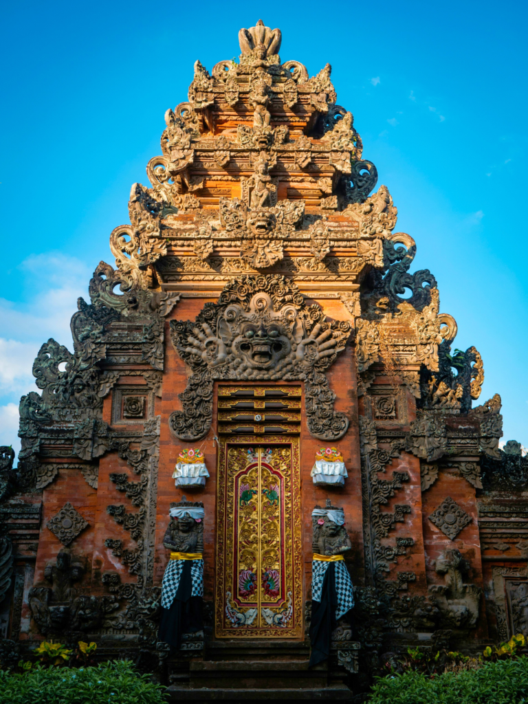 Ornately carved entrance of a traditional Balinese temple under a blue sky