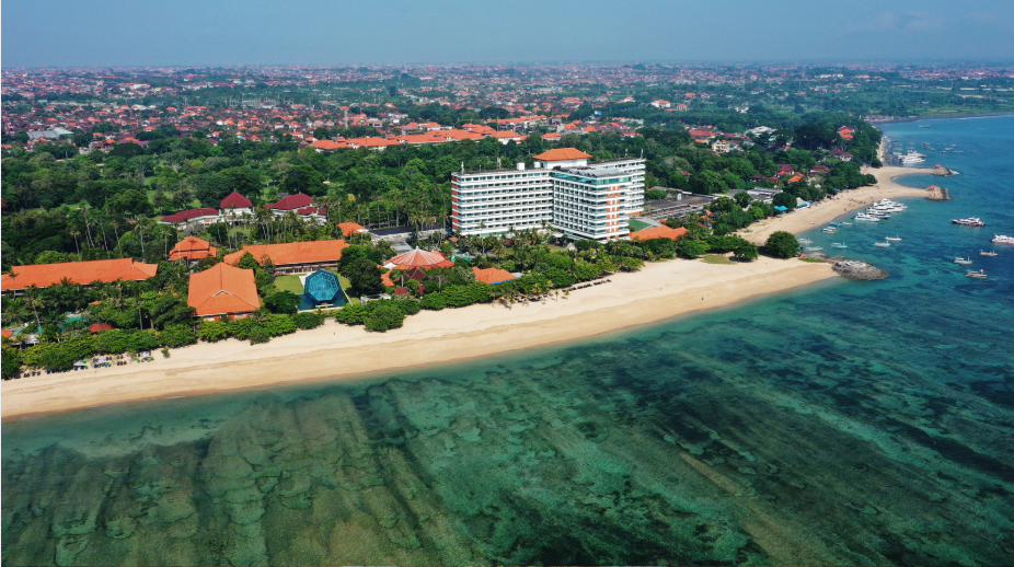 Aerial view of Sanur Beach in Bali, with beachfront resorts, white sand and shallow turquoise water.