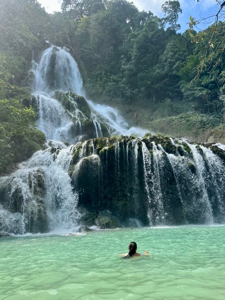 A swimmer in the turquoise pool beneath Lapopu Waterfall, featured in our One Week in Sumba itinerary.